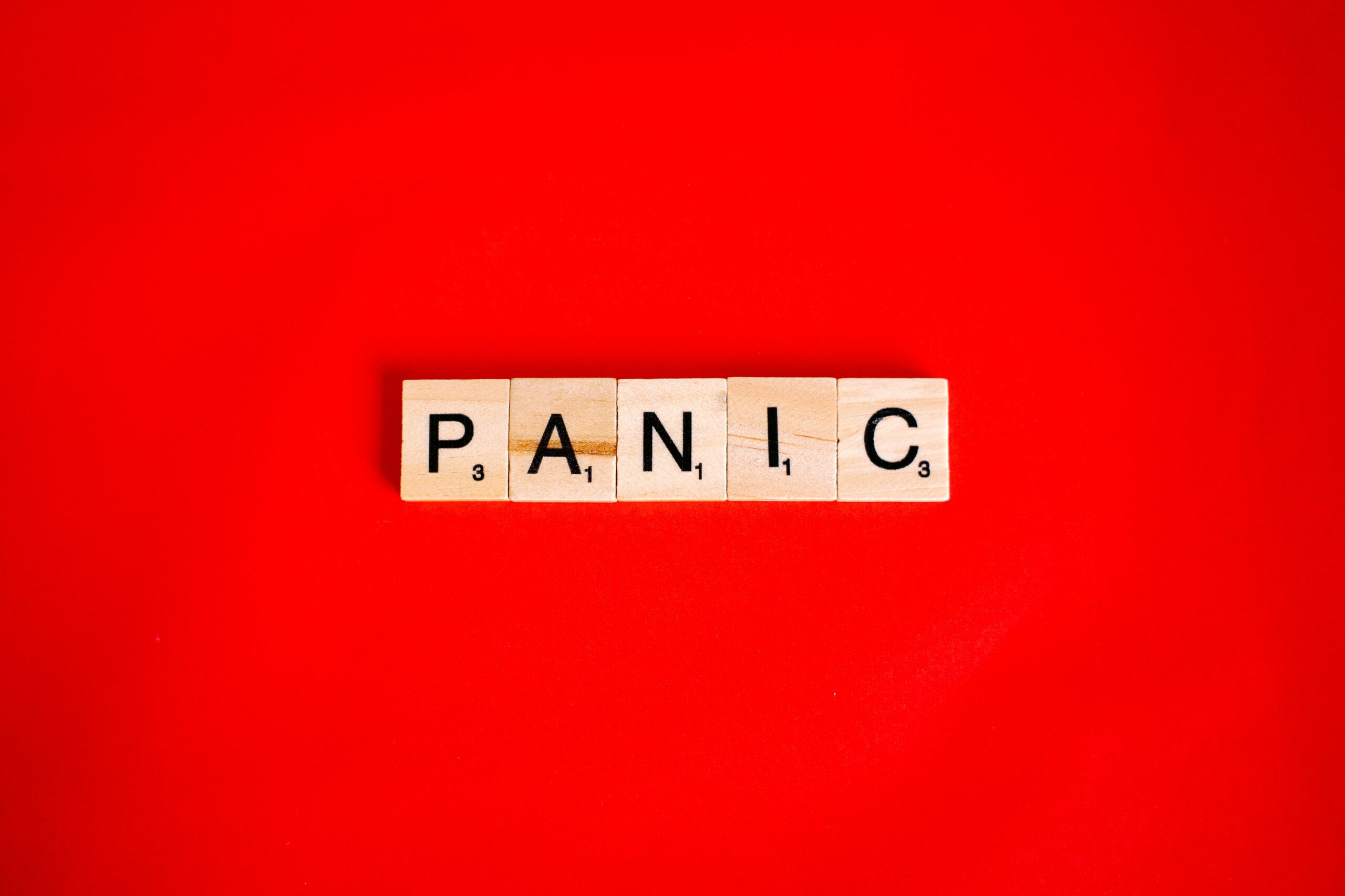 Tekst Panic, svako slovo na zasebnoj bež kockici, na crvenoj pozadini
